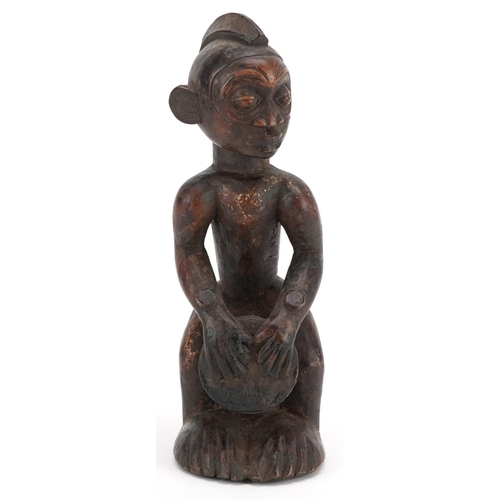 200 - An African figure of a drummer, late 19th/early 20th century, the head shaved with a coxcomb, a cyli... 