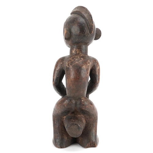 200 - An African figure of a drummer, late 19th/early 20th century, the head shaved with a coxcomb, a cyli... 