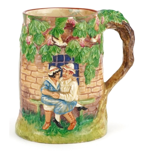 282 - A Crown Devon musical tankard, circa 1930, moulded and coloured in relief with lovers outside a forg... 