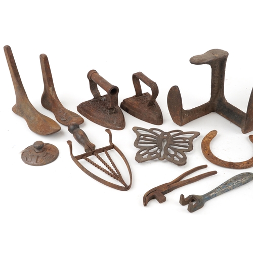 1129 - A collection of Victorian cast iron and metalware including flat irons, shoe lasts and horseshoes.