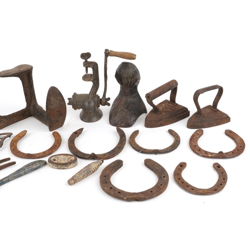 1129 - A collection of Victorian cast iron and metalware including flat irons, shoe lasts and horseshoes.