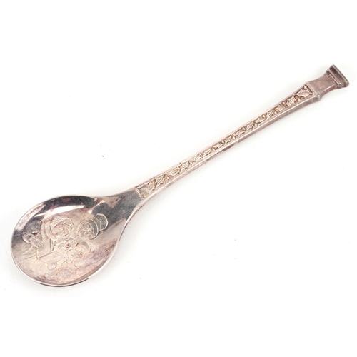 559 - A silver Christmas spoon, London 1975, the bowl cast with Victorian carol singers, the stem cast wit... 