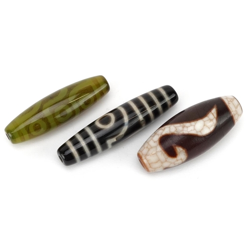 305 - Three Chinese polished stone beads, 20th century, the largest 6cm in length.