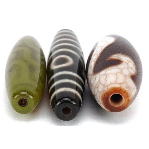 305 - Three Chinese polished stone beads, 20th century, the largest 6cm in length.