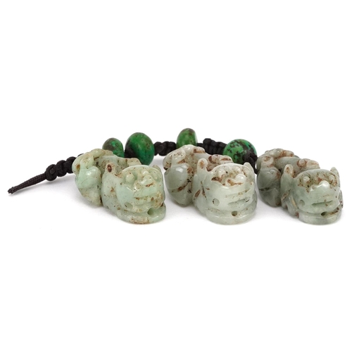 307 - Three Chinese carved celadon jade beads in the form of Foo dogs, early 20th century, 2cm in length.