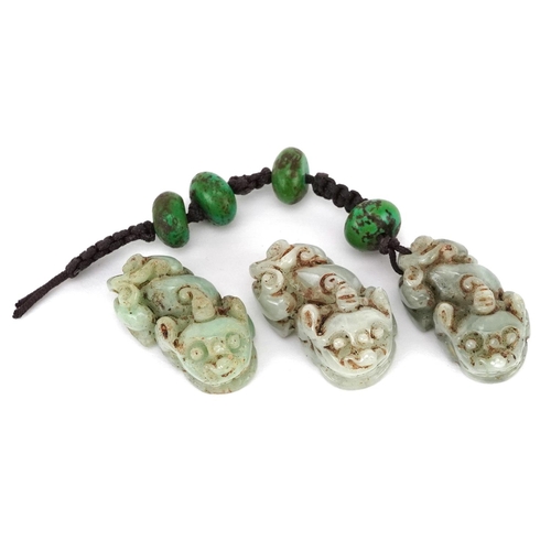 307 - Three Chinese carved celadon jade beads in the form of Foo dogs, early 20th century, 2cm in length.