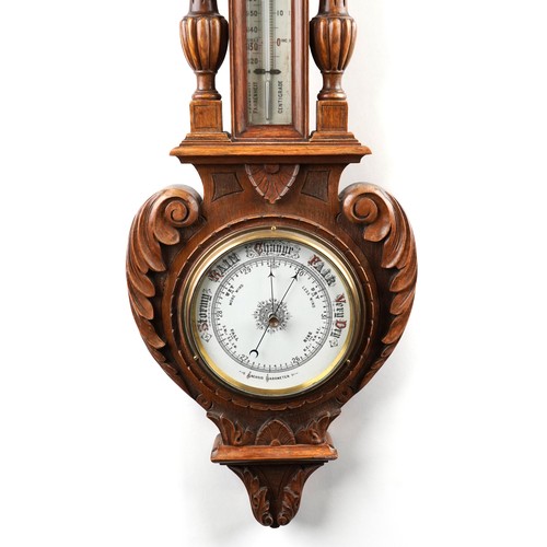 2170 - A late Victorian carved oak wall hanging aneroid barometer, 99cm in length.