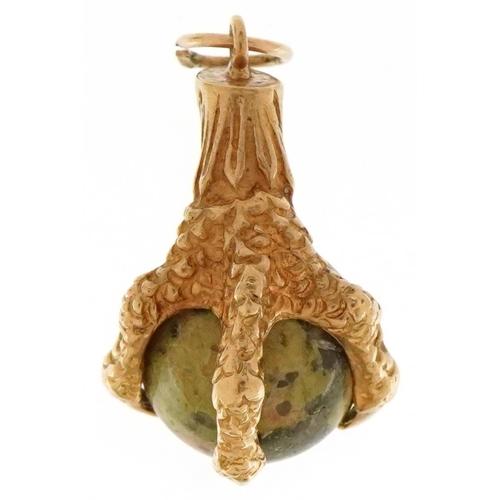 3410 - A yellow metal and hardstone charm in the form of a claw clutching a ball, 28.5mm high, 5.9g.