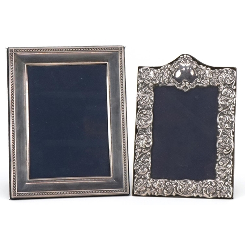 566 - Two rectangular silver easel photo frames, one profusely embossed with flowers and foliage, the larg... 