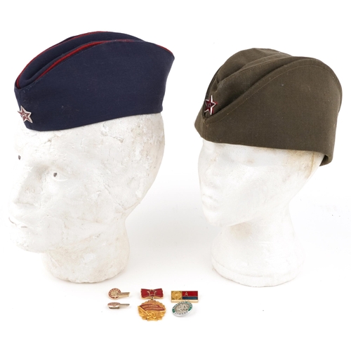 2456 - Two Russian military interest cloth side caps and a group of enamelled badges.