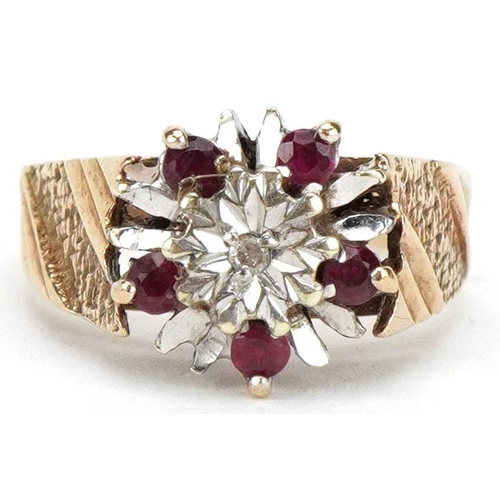 3477 - A 9ct gold diamond and ruby flower head ring with engine turned shoulders, size L, 3.3g, housed in a... 