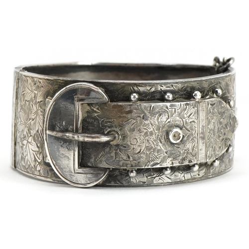 3445 - A Victorian silver belt buckle design hinged bangle with engraved foliate decoration, indistinct hal... 