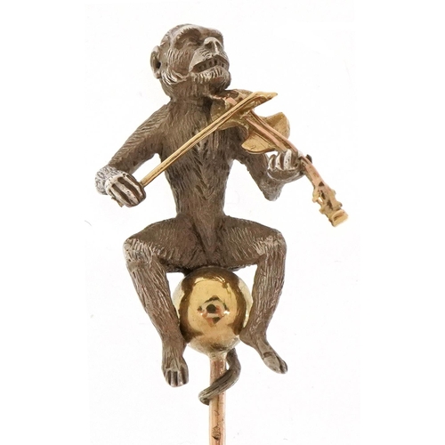 3146 - An antique unmarked gold, silver and yellow metal stickpin in the form of a monkey playing a violin,... 