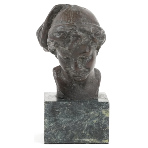 1115 - A patinated bronze head and shoulders bust of a young male wearing a hat, raised on a green marble b... 