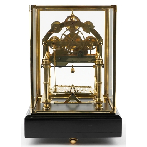 97 - A Congreve style rolling ball clock housed under a glazed brass display case with ebonised base and ... 