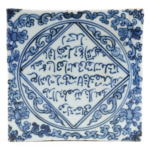 114 - An Islamic pottery tile hand painted with script amongst foliage, 19.5cm x 19.5cm.