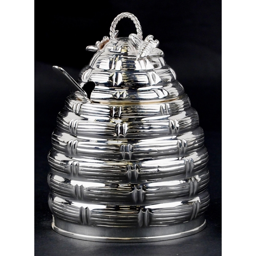 1112 - A silver plated beehive design preserve jar with spoon and glass liner, 12cm high.