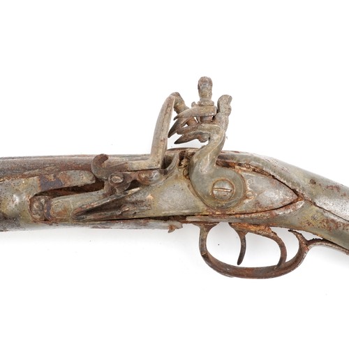 2555 - An antique Middle Eastern double barrel flintlock rifle, the wooden stock carved carved with a figur... 