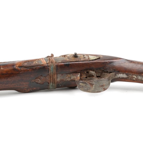 2554 - An antique Middle Eastern double barrel flintlock rifle, the wooden stock carved with a serpent head... 