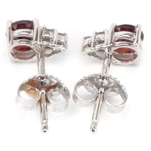 3180 - A pair of 18ct white gold garnet solitaire and diamond stud earrings, 7.2mm high, total 1.3g.