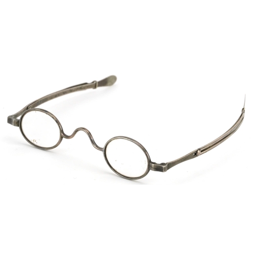 131 - A pair of early 20th century metal framed adjustable spectacles together with a case.