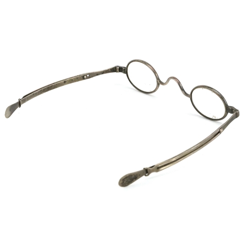 131 - A pair of early 20th century metal framed adjustable spectacles together with a case.