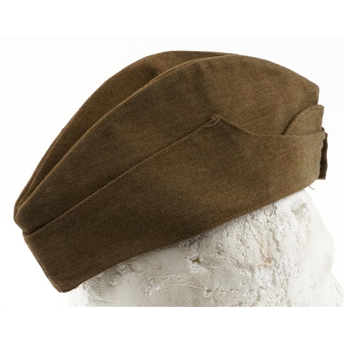 2477 - A British military World War II side cap with Royal Kent West cap badge, stamped marks to the interi... 