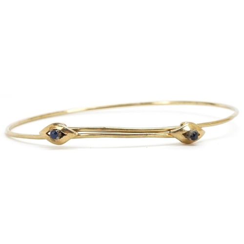 3105 - A 14ct gold adjustable bangle set with two sapphires, 6.5cm in diameter, 4.5g.