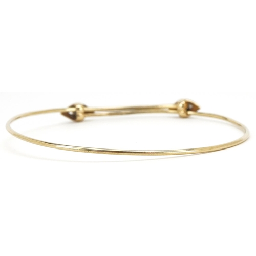 3105 - A 14ct gold adjustable bangle set with two sapphires, 6.5cm in diameter, 4.5g.