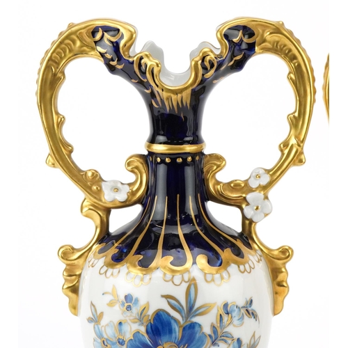 214 - A pair of Royal Dux Czechoslovakian porcelain vases with gilt twin handles and hand painted with flo... 