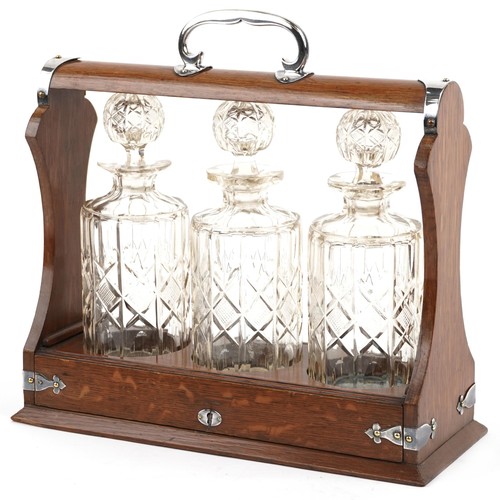 442 - An Edwardian style oak three bottle tantalus with silver plated mounts and key, 35cm wide x 34cm hig... 