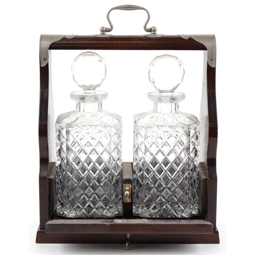 1618 - A 20th century mahogany cased two bottle tantalus, the decanters with cut glass decoration, with key... 