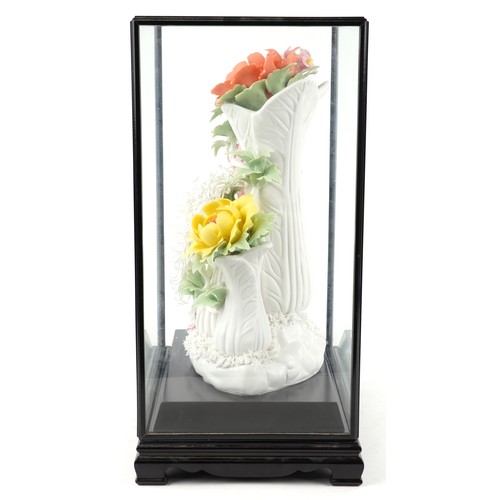 2604 - A Chinese porcelain hand painted floral sculpture, modern, within an ebonised glazed display case on... 