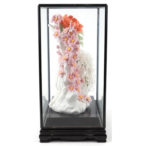 2604 - A Chinese porcelain hand painted floral sculpture, modern, within an ebonised glazed display case on... 