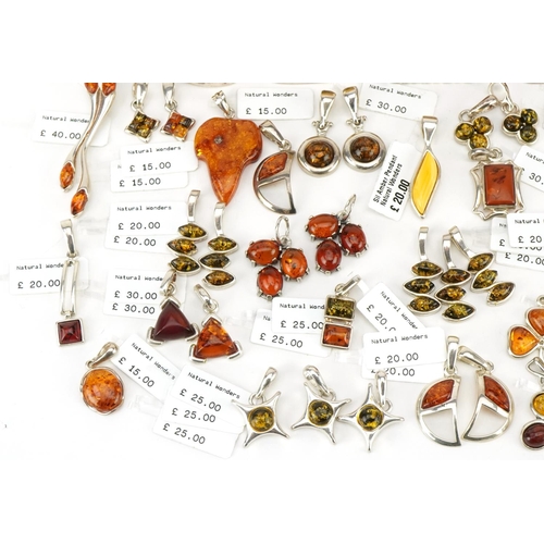 3726 - A large collection of silver mounted amber pendants, predominantly with Natural Wonders labels, the ... 