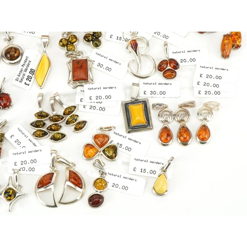 3726 - A large collection of silver mounted amber pendants, predominantly with Natural Wonders labels, the ... 