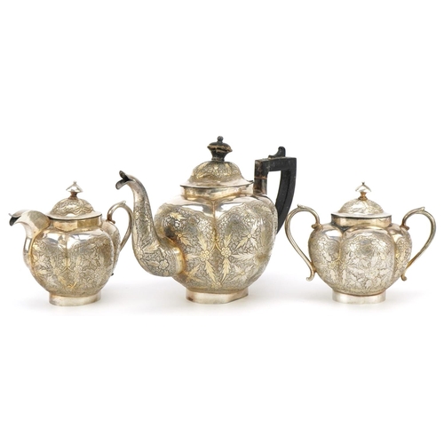 558 - An Indian white metal tea service profusely engraved with flowers and foliage, the teapot 20cm in le... 