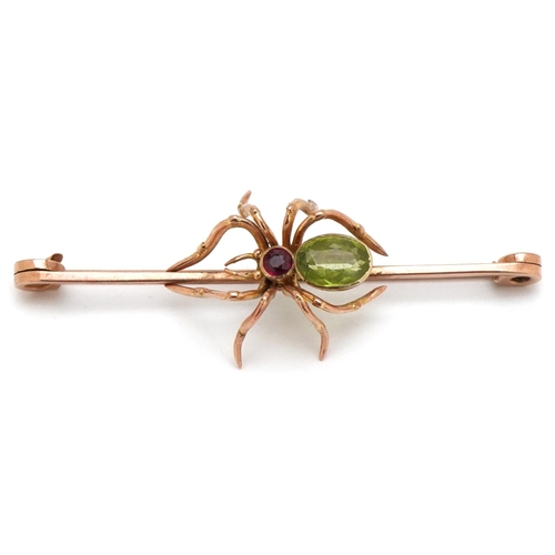 An antique unmarked rose gold bar brooch in the form of a spider set with green amethyst and a ruby, 6.5cm wide, 6.4g.