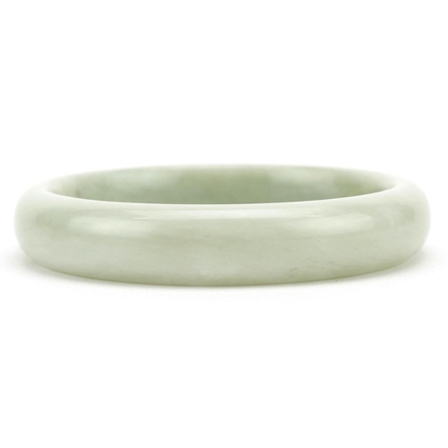 3409 - A Chinese pale green jade style stone bangle, 7.5cm in diameter, 51.5g.