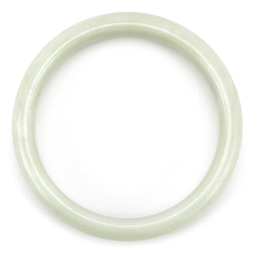 3409 - A Chinese pale green jade style stone bangle, 7.5cm in diameter, 51.5g.