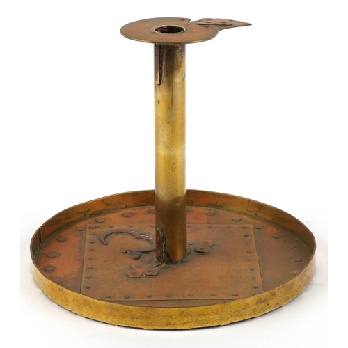 105 - An Arts & Craft brass candlestick with applied copper stylized motif, 18cm high.