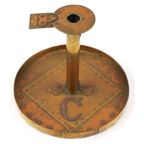 105 - An Arts & Craft brass candlestick with applied copper stylized motif, 18cm high.