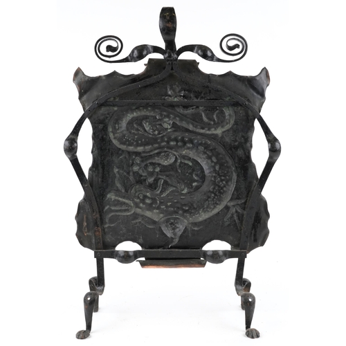 167 - A late 19th century Arts & Crafts wrought iron and embossed copper fire screen decorated with a drag... 