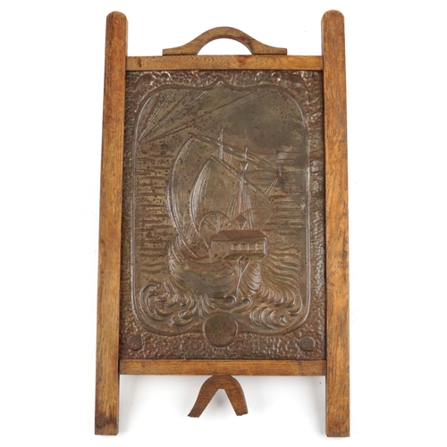 458 - An Edwardian Arts & Crafts oak and embossed tin fire screen decorated with a boat, 72cm x 42cm.