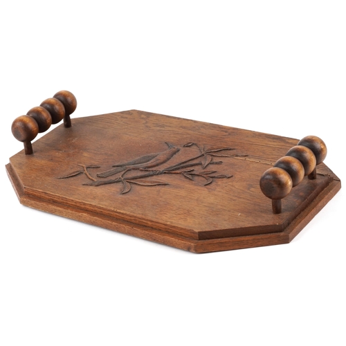 398 - An Arts & Crafts oak canted rectangular tray, the top carved with a bird, fitted with two bobbin tur... 