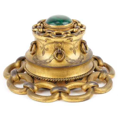 104 - An Arts & Crafts brass inkwell, the hinged lid set with a cabochon malachite panel and ring turned h... 