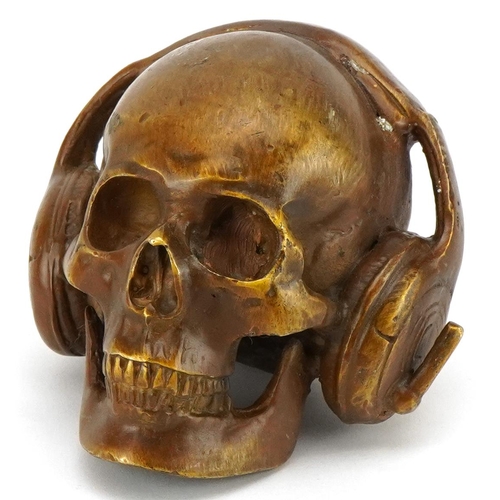 1620 - A patinated bronze study of a human skull wearing headphones, 7.5cm high.