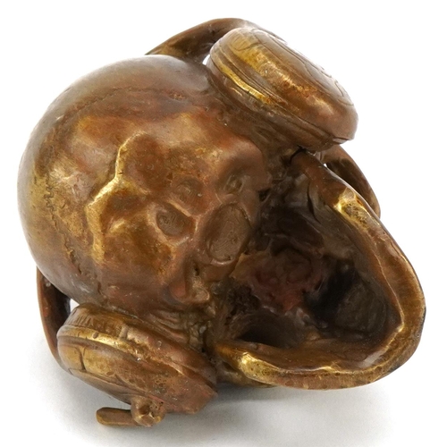 1620 - A patinated bronze study of a human skull wearing headphones, 7.5cm high.