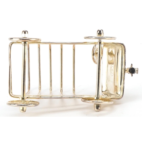 1598 - A silver plated five slice toast rack in the form of a car with rotating wheels, 15cm in length.