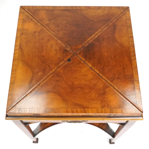 2134 - A late 20th century walnut envelope card table with cross banded decoration, the rotating top raised... 